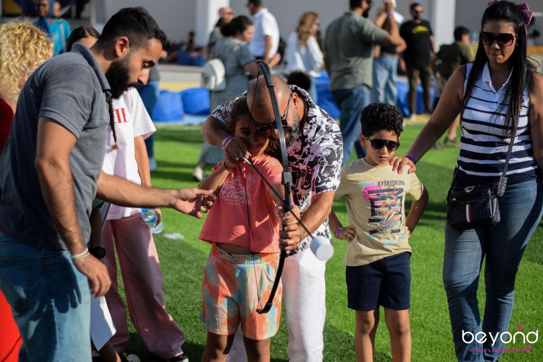 A father helping his kids try archery at a Family Funday