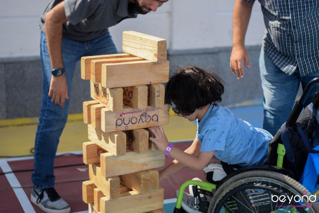 A child playing giant Jenga with family at a Beyond Family Funday